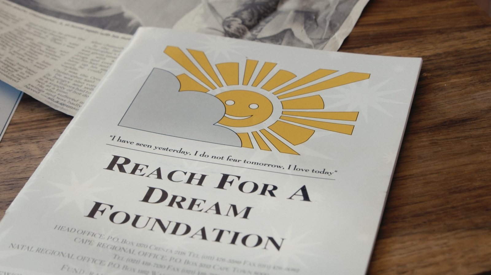 A Reach For A Dream Foundation booklet beside the newspaper clippings