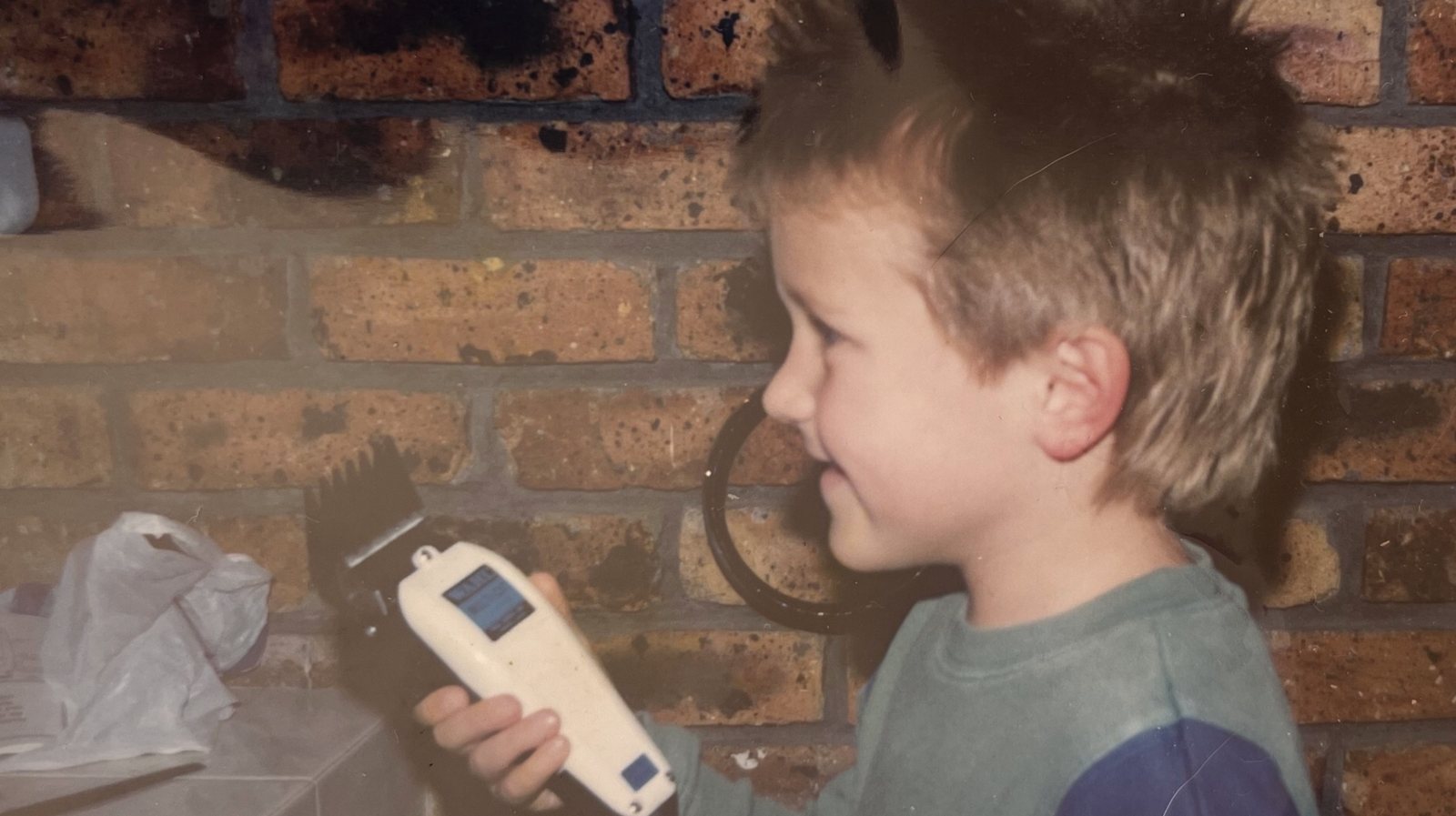 Chris as a boy holding hair clippers before shaving his head