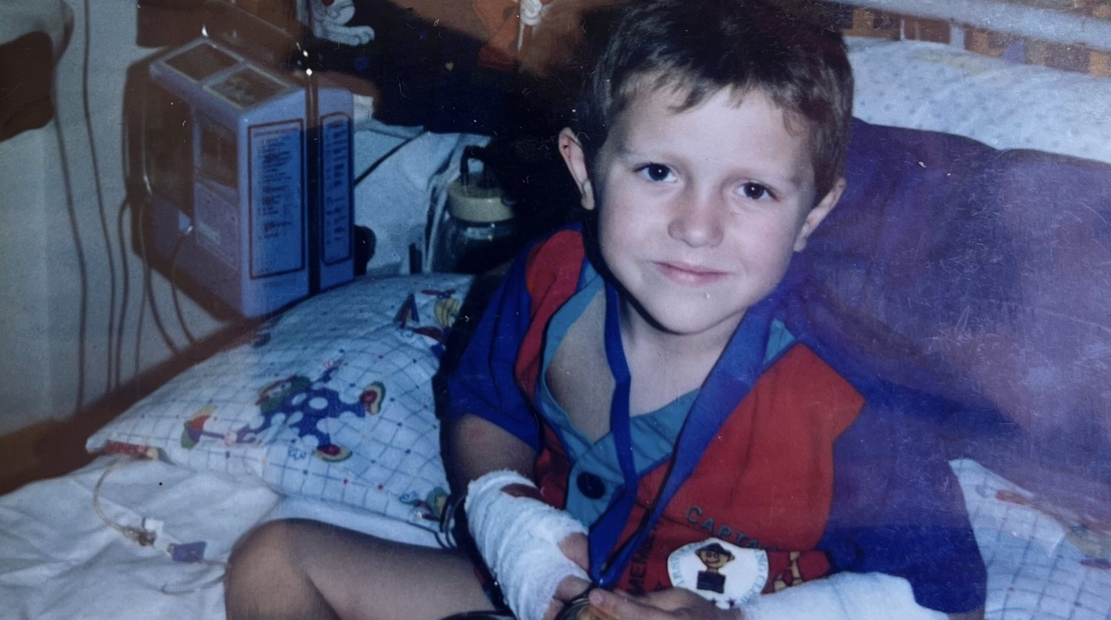 Chris sitting on a hospital bed with a drip line in his arm