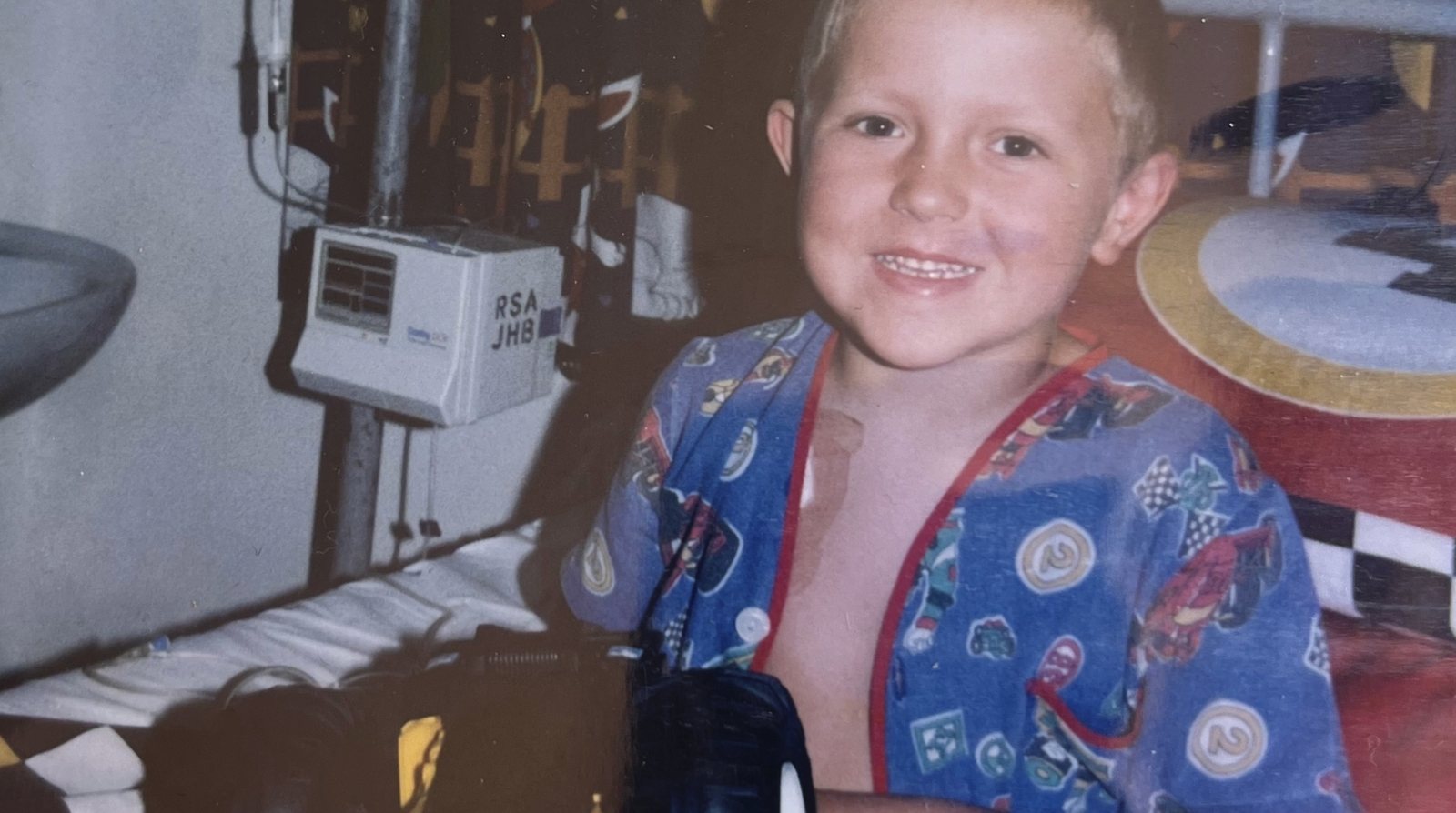 Chris smiling in hospital pyjamas beside his drip stand