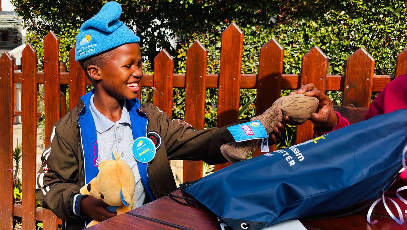 A boy at a garden table unwrapping a gift in the afternoon sun