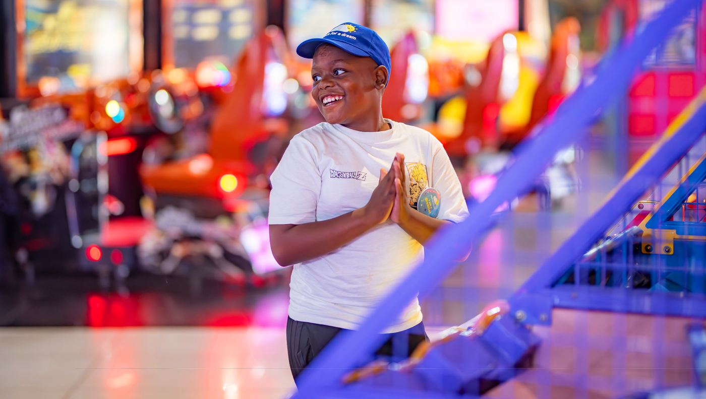 A boy at an arcade, hands clasped together in delight